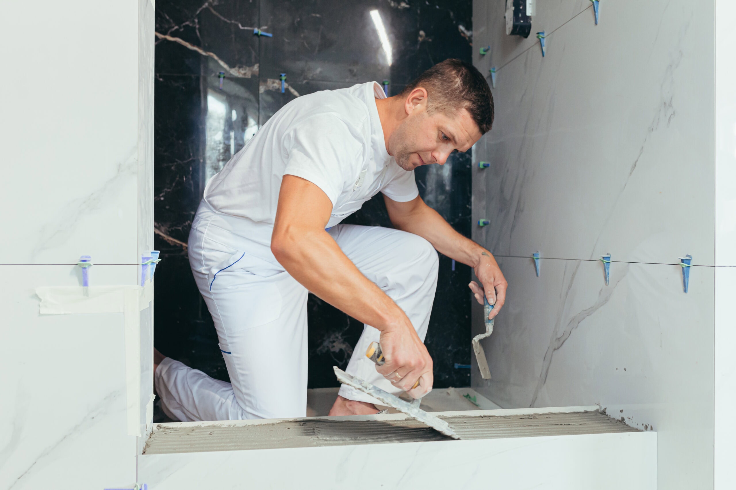 professional worker mounts ceramic tiles for bathroom remodeling